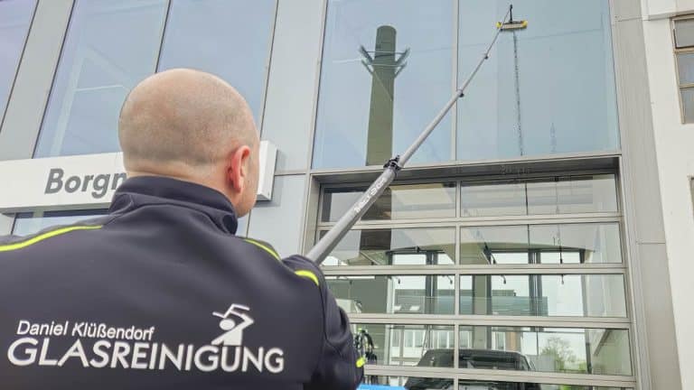Daniel Klüßendorf reinigt ein Fenster eines Gebäudes